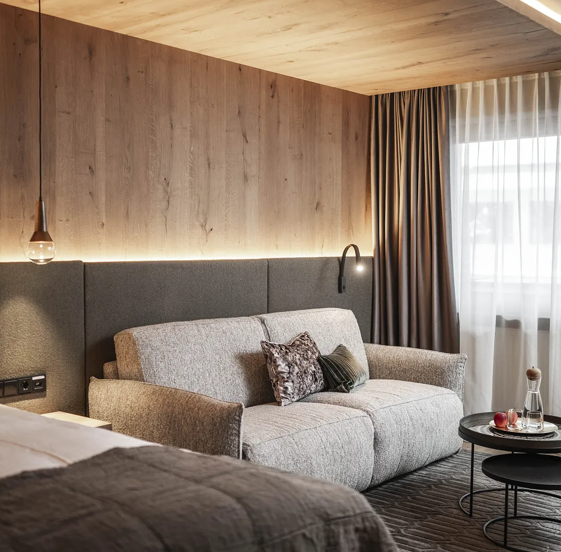 Modern eingerichtetes Hotelzimmer mit Sofa, Lampe, Bett und kleinem Tisch.