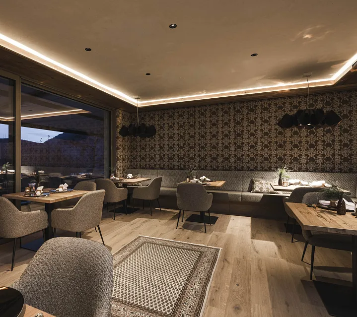 Modernes Restaurant mit Holz- und Polstermöbeln in schickem Ambiente, abends in Tirol, Kitzbühel.