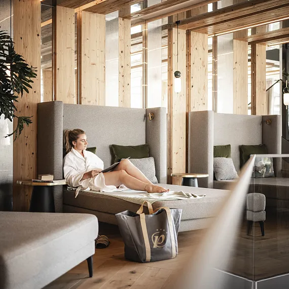 Person entspannt in einem modern gestalteten Holz-Innenraum auf einer Liege.