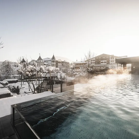Winterlandschaft mit Hotel in Kitzbühel, Tirol, neben beheiztem Außenpool mit Dampf.
