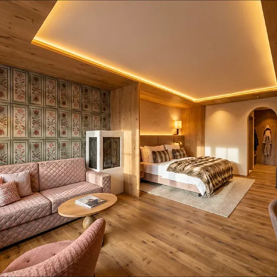 Luxuriöses Hotelzimmer in Kitzbühel mit Doppelbett, Sofa, Holzwänden und stimmungsvoller Beleuchtung.