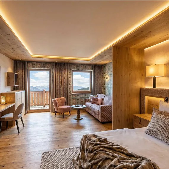 Modernes Hotelzimmer mit Holzmöbeln und Blick auf Berge durch große Fenster.