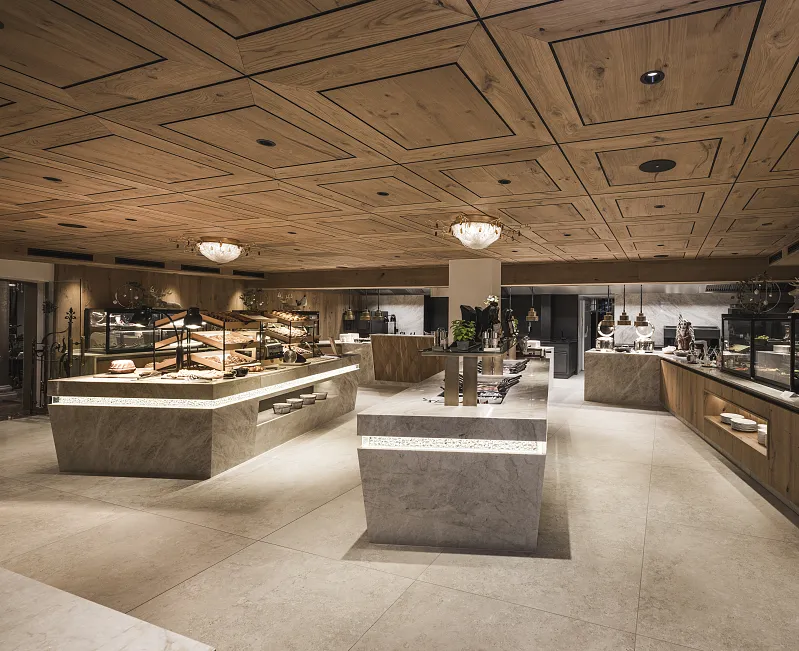 Modernes Restaurantinterieur mit Holzelementen und mehreren Buffetstationen in Kitzbühel, Tirol.