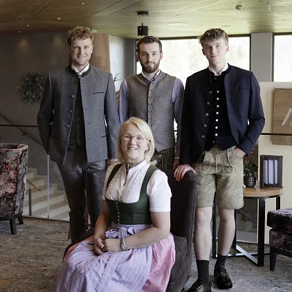 Vier Personen in traditioneller Tiroler Tracht in einem modern eingerichteten Raum.