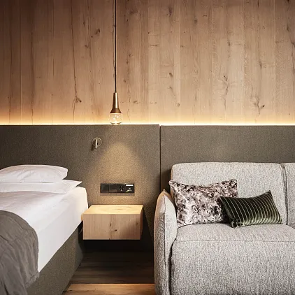 Modernes Hotelzimmer mit Holzvertäfelung, einem Bett und einer Couch in neutralen Tönen.