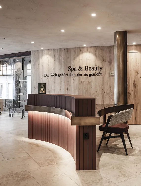 Moderner Spa-Empfangsbereich mit Holzverkleidung und Beleuchtung, zwei Stühlen und dekorativen Elementen.