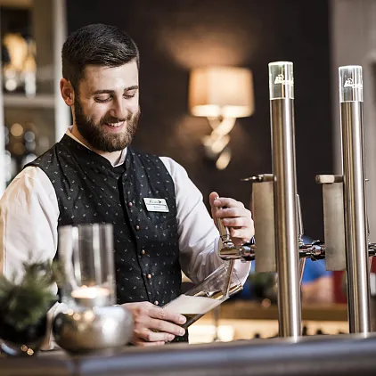 Ein Barkeeper zapft Bier an einer Theke in einer gemütlichen Bar.