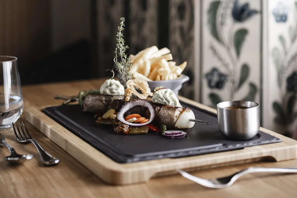 Gegrillte Lammkoteletts mit Kräuterbutter und Pommes frites auf einem Teller in einem rustikalen Esszimmer.