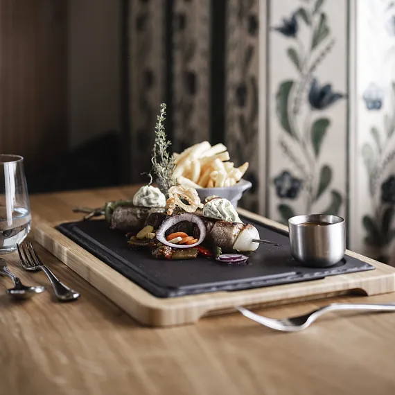 Gegrillte Lammkoteletts mit Kräuterbutter und Pommes frites auf einem Teller in einem rustikalen Esszimmer.
