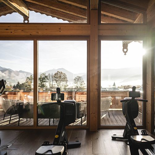 Zwei Ergometer vor großen Fenstern mit Blick auf die Berglandschaft in Kitzbühel, Tirol.