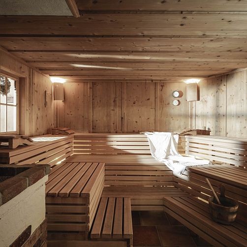 Leere Sauna aus Holz mit Holzbänken und Wandthermometern an den Wänden.