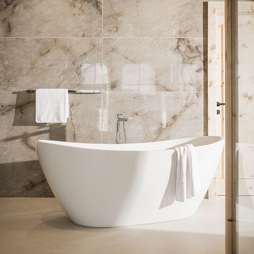 Modernes Badezimmer mit freistehender Badewanne und Handtuch an Marmorwand.