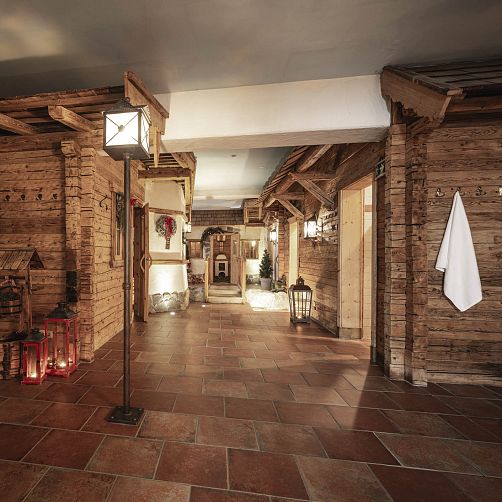 Gemütlicher, rustikaler Flur mit Holzwänden, roten Laternen und dekorativem Baum in alpenländischem Stil.