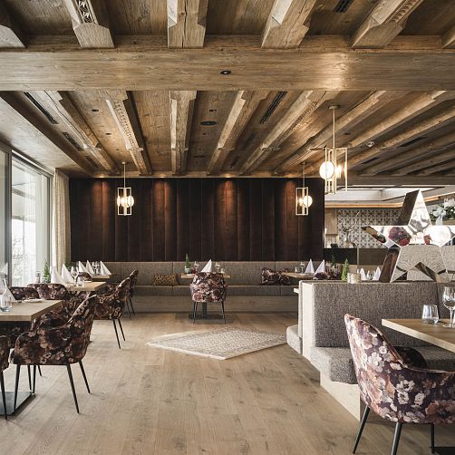 Modernes Restaurantinterieur mit Holzbalkendecke, stilvollen Leuchten und eleganten Sitzbereichen.