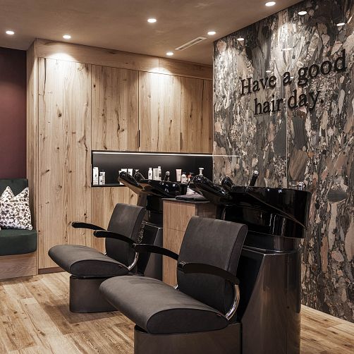 Moderner Friseursalon mit zwei Waschplätzen und stylischer Holz- und Steinoptik, Schriftzug "Have a good hair day."