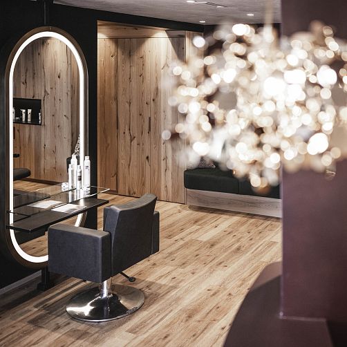 Moderner Friseursalon mit Holzverkleidung, Spiegel und schwarzem Stuhl.