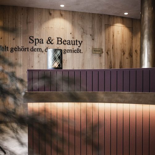 Empfangsbereich eines Spa & Beauty Studios mit Holzverkleidung und dekorativem Kerzenhalter.