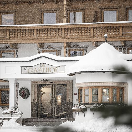 Schneebedecktes Gasthaus mit Holzbalkon in Kitzbühel.