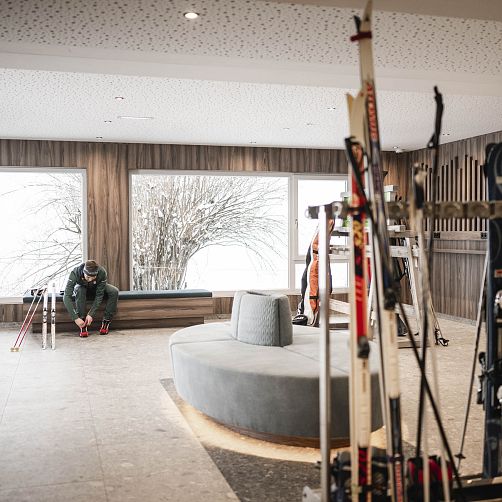 Leerer Skiraum mit Skiern und einem sitzenden Mann in Tirol, Kitzbühel.