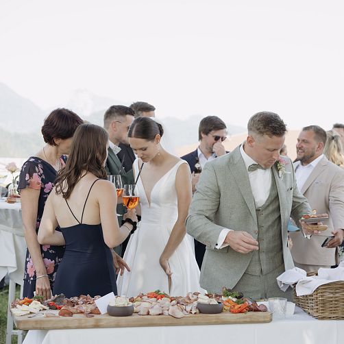 Hochzeitsgäste bedienen sich an einem Buffet im Freien, umgeben von Bergen in Tirol.