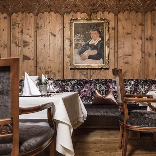 Rustikales Restaurant mit Holzwänden, festlich gedecktem Tisch und traditionellem Porträt an der Wand.