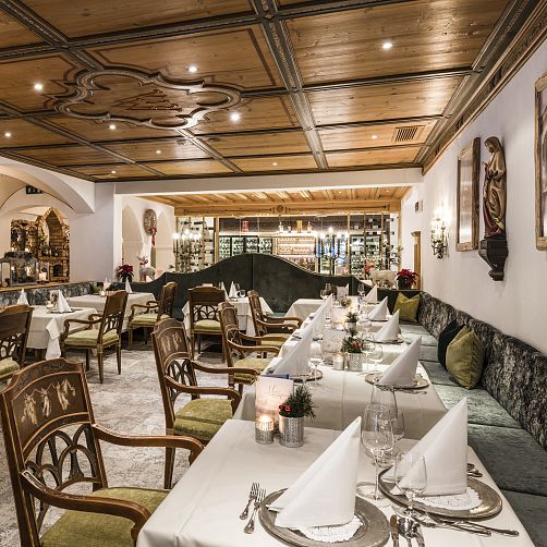 Elegantes Restaurant in Tirol mit traditioneller Holzdecke, Tischdekoration und Stühlen in einem warmen Ambiente.