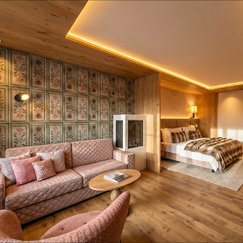 Geschmackvoll eingerichtetes Hotelzimmer mit gemütlicher Sitzecke, Tapeten mit floralem Muster und einem Doppelbett.