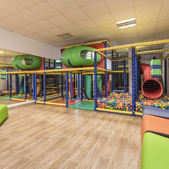 Indoor-Spielplatz mit Klettergerüsten und Bällebad auf Holzboden.